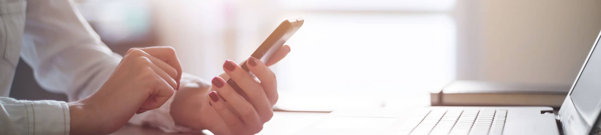 Woman using mobile phone and laptop