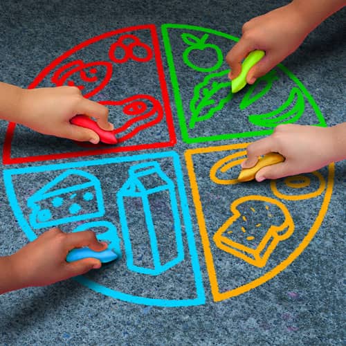 Children drawing food groups in coloured chalk in Wrexham school